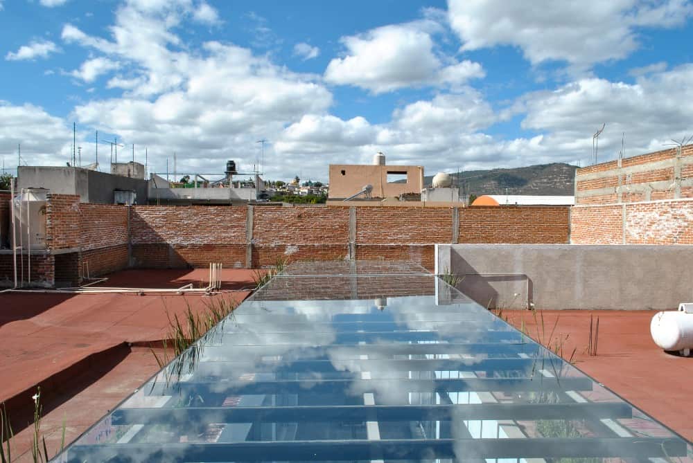 这是一个近距离观察由金属梁支撑的庭院上方的玻璃天花板，可以看到有陶土地板的屋顶。