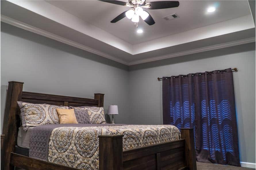 主卧室的特色是一张深色木床和一个装有风扇的托盘天花板。