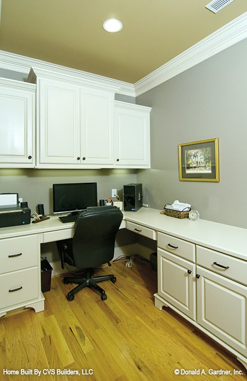 家庭办公室，白色橱柜和内置办公桌搭配皮革转椅。