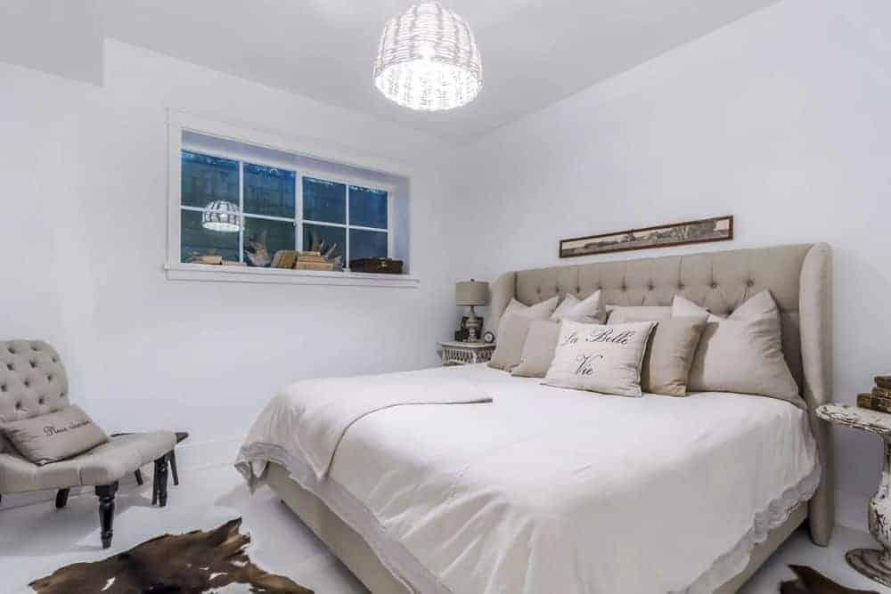 卧室用牛皮地毯、不良表和一个匹配的米色植绒的床上舒适的椅子上。