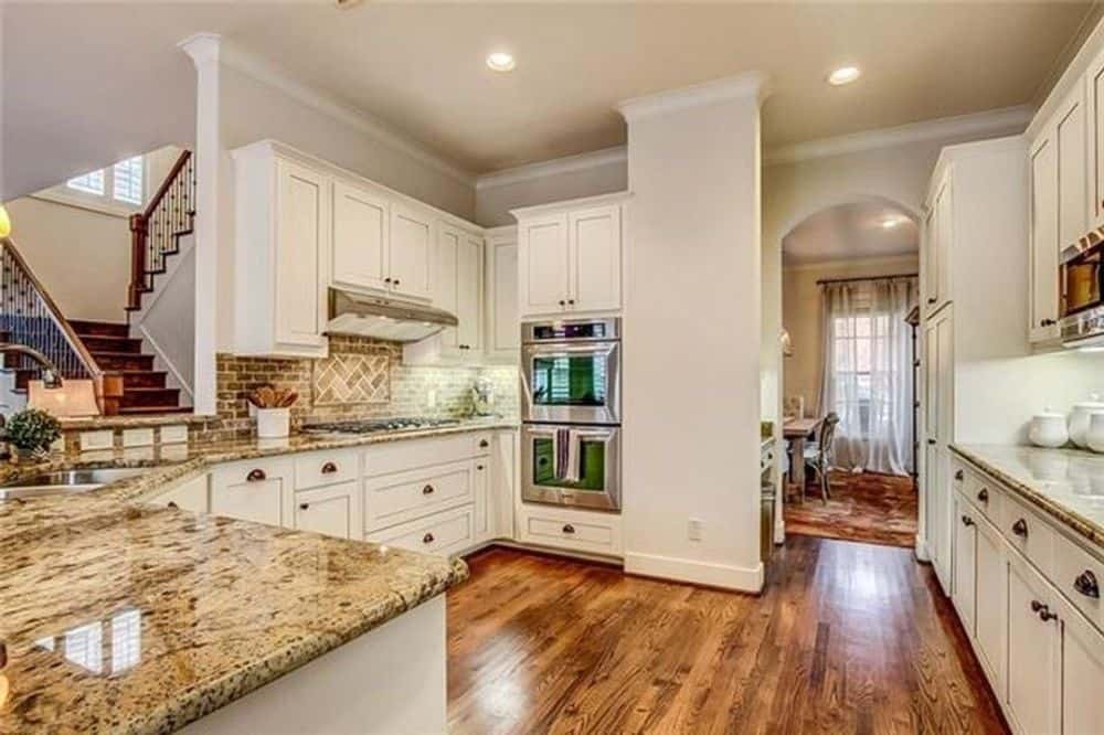 厨房以白色橱柜、花岗岩台面、内置炉灶和砖后挡板为特色。