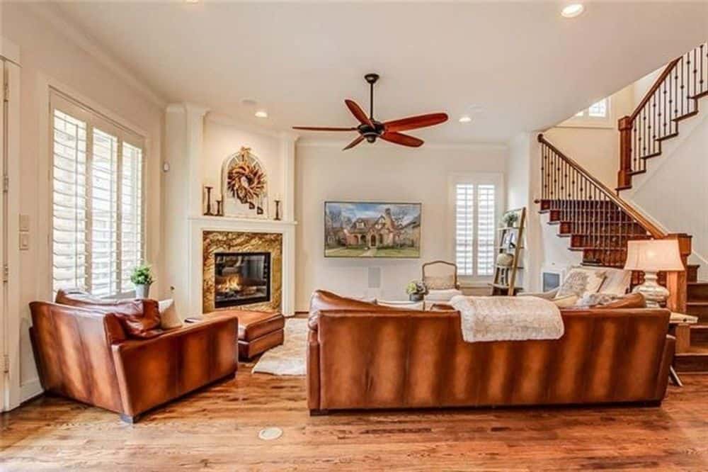 家庭娱乐室配有棕色真皮座椅、角落壁炉和壁挂式电视。