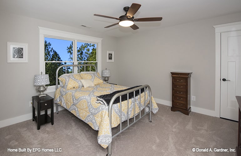 这间卧室配有吊扇和铺有地毯的金属床。