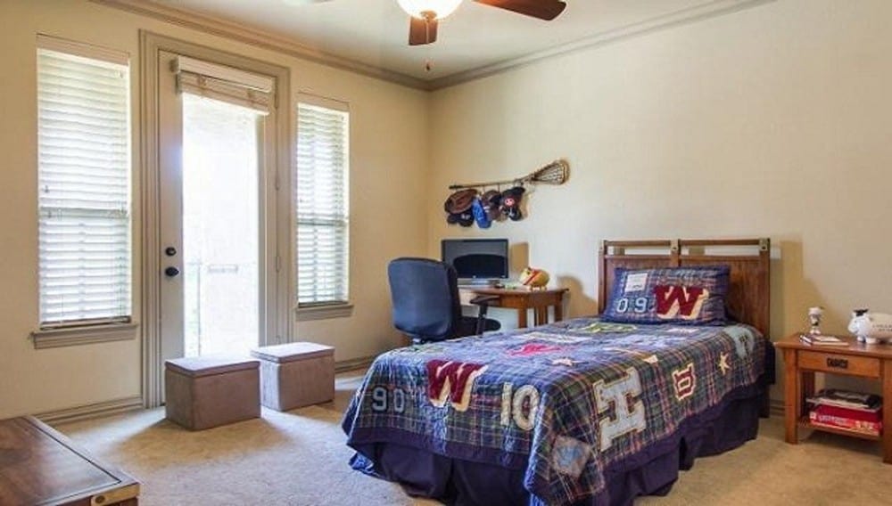 这间卧室里有木制家具和与米色墙壁相配的地毯地板。