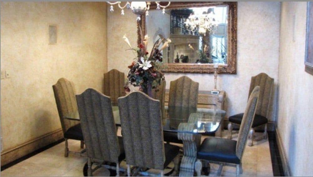 正式的餐厅，有一面华丽的镜子和一张玻璃桌，配有皮革软垫椅子。