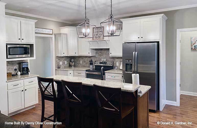 厨房配备了不锈钢器具、花岗岩台面、白色橱柜和一个两层岛台。