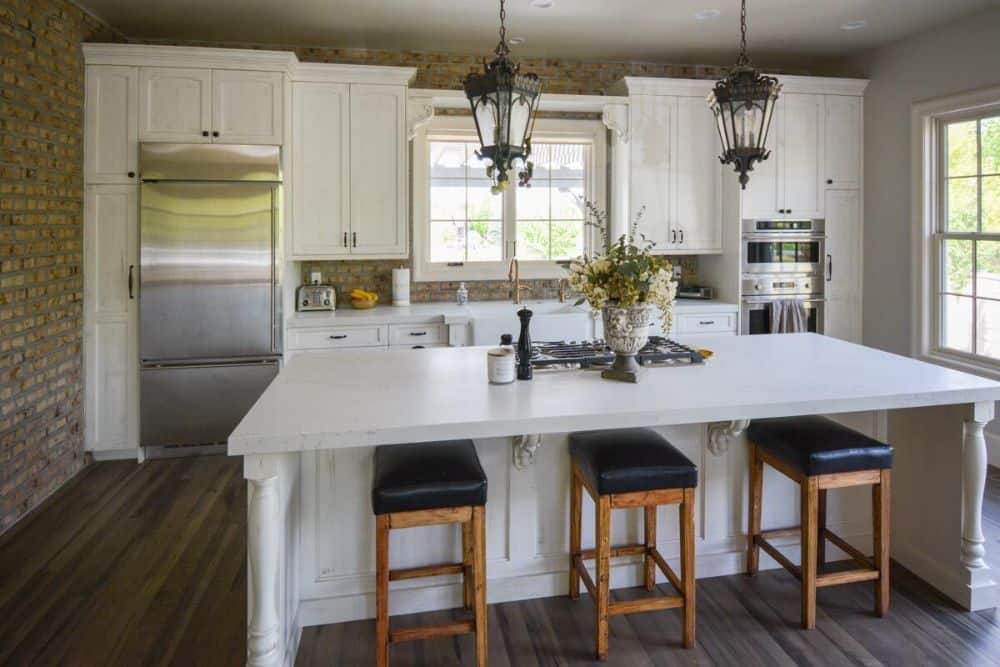 厨房配有不锈钢电器、白色的橱柜,早餐岛内衬皮革坐垫凳子。