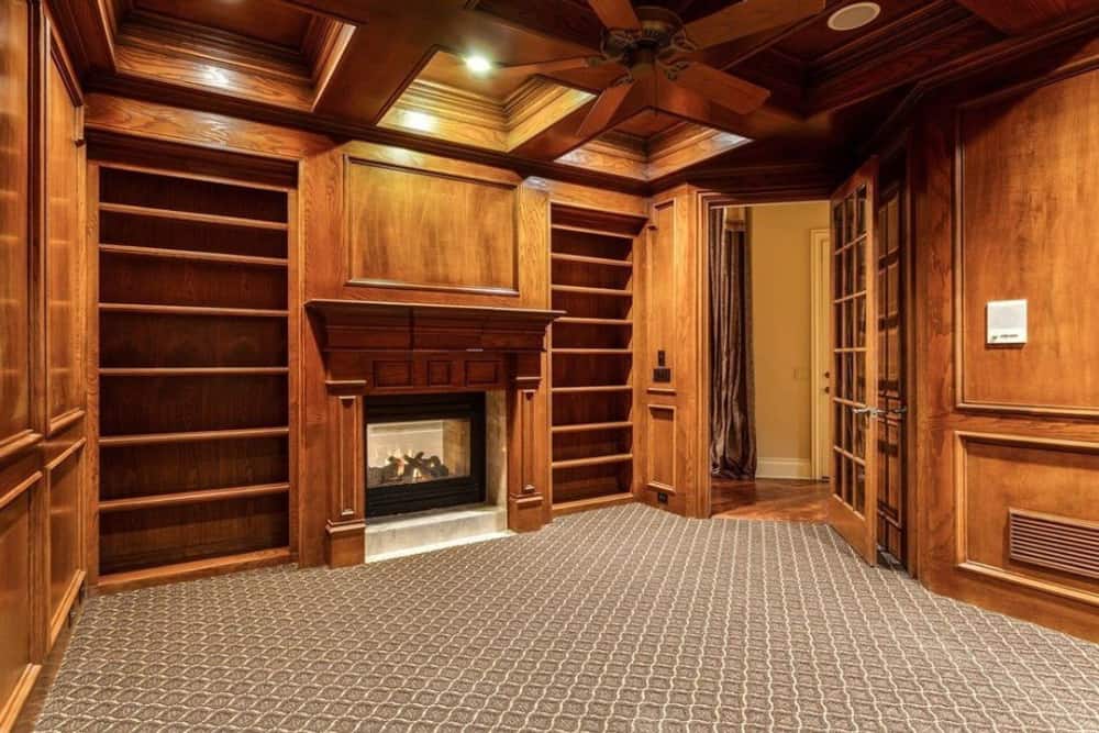 书房里有一座双面壁炉和木质嵌壁式壁炉，与格子天花板相匹配。