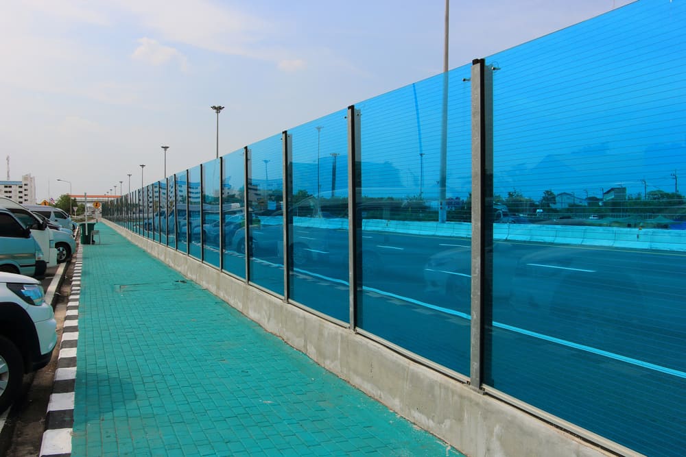 这是一条用隔音玻璃制成的隔音屏障环绕的高速公路的近景。