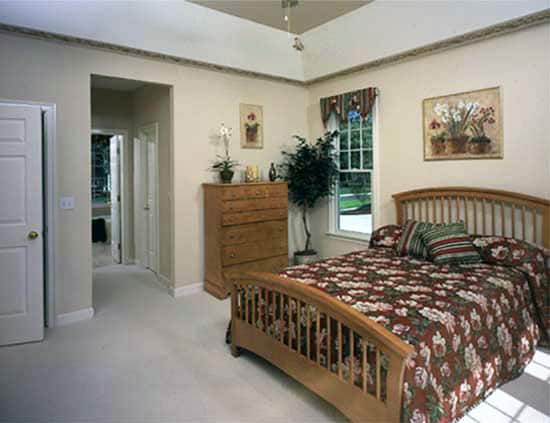 主卧室有木制家具、地毯地板和装饰着米色墙壁的花卉艺术品。