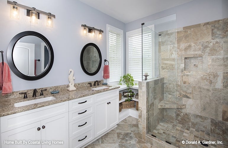 主浴室有一间步入式淋浴间和一个双洗手池梳妆台，配有圆形镜子。