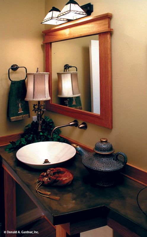 化妆间里有一面木制镜框镜子和一个洗手台，上面有一个水槽。