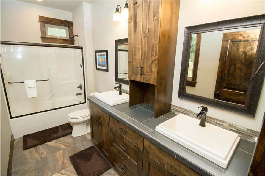 主浴室有一个双洗手台，一个马桶，一个带角落座位的步入式淋浴间。