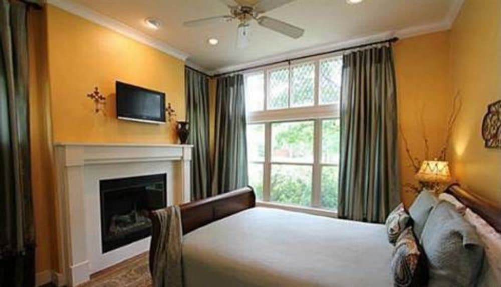 这间卧室设有壁挂式电视、壁炉和一扇大窗户，可邀请自然光进入。
