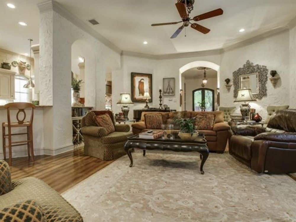 家庭娱乐室，有织物和皮革座椅，还有一张木制咖啡桌，上面铺着一张老式地毯。