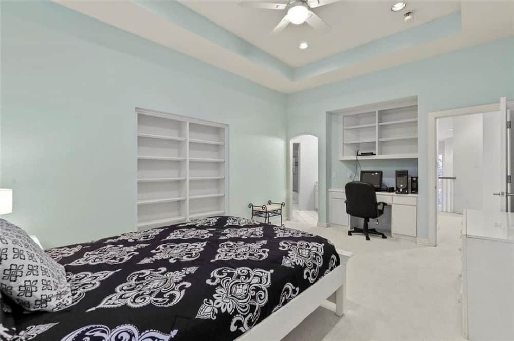 这间卧室提供白色嵌壁式家具和一张配有皮革转椅的桌子。