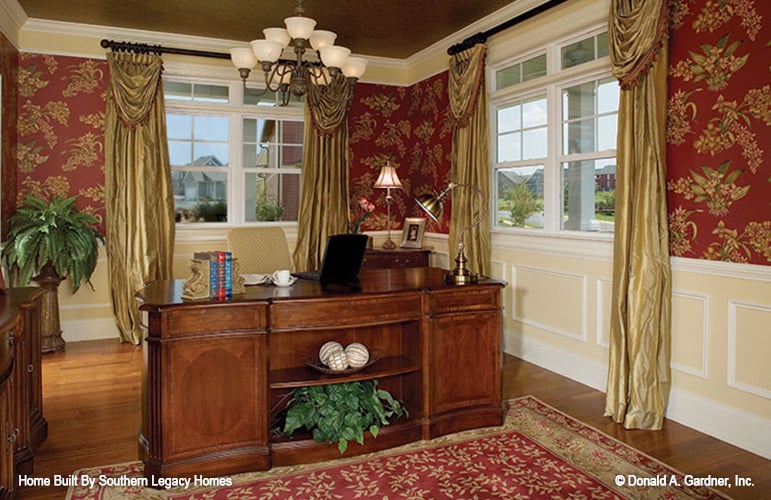 家庭办公室，有木桌，护壁墙和经典的红色图案地毯，与花卉壁纸相匹配。