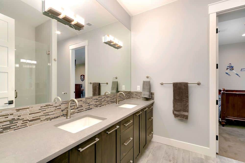 这间浴室设有一个带双水槽的大梳妆台和一面无框镜子。