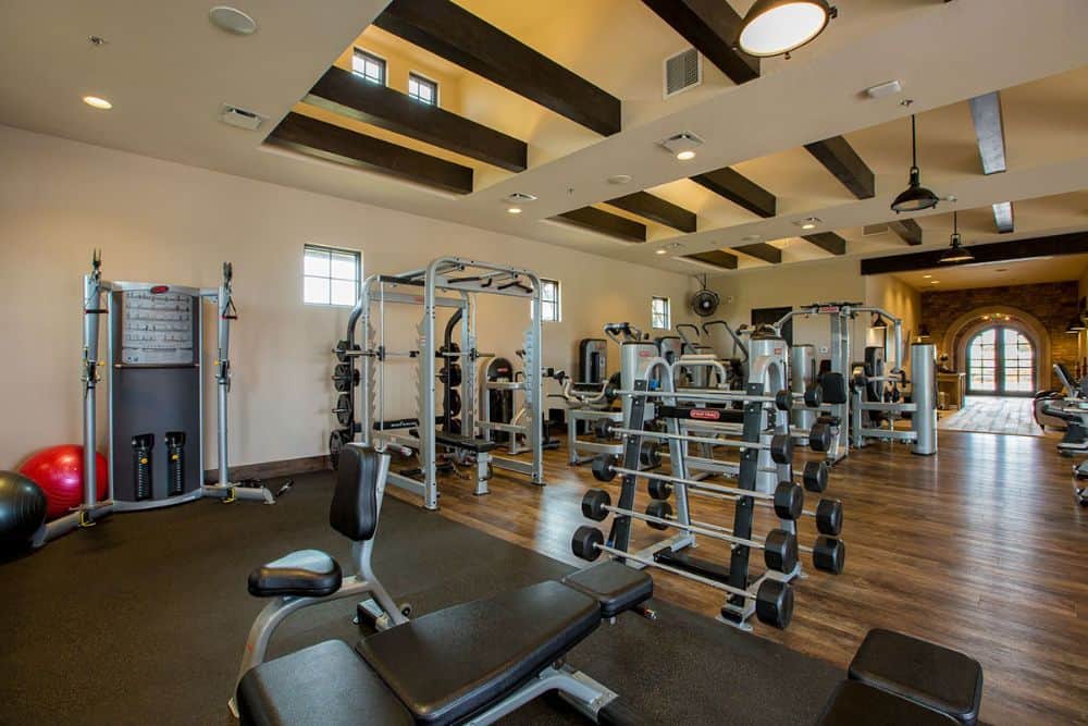 一个设备齐全的健身房，硬木地板和横梁天花板。