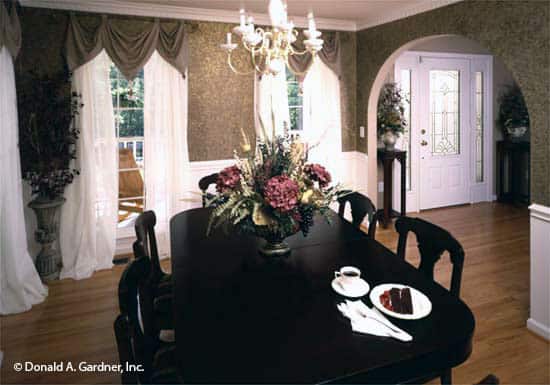 正式的餐厅，椭圆形的餐厅和高大的窗户，穿着优雅的窗帘和透明的窗帘。