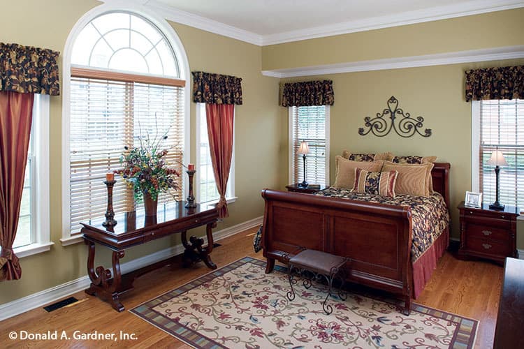主卧室的特色是木制家具、花卉区域地毯和大量装饰有图案帷幔的窗户。