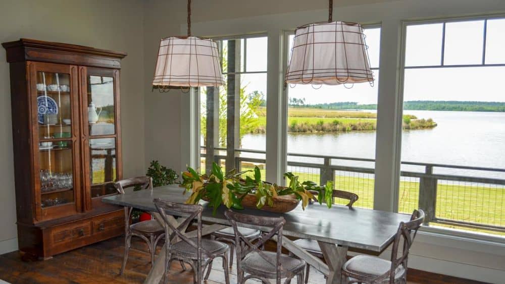 餐厅区有一个木制的瓷器柜，一个长方形的餐厅，和三面镶板的窗户，可以俯瞰湖泊。