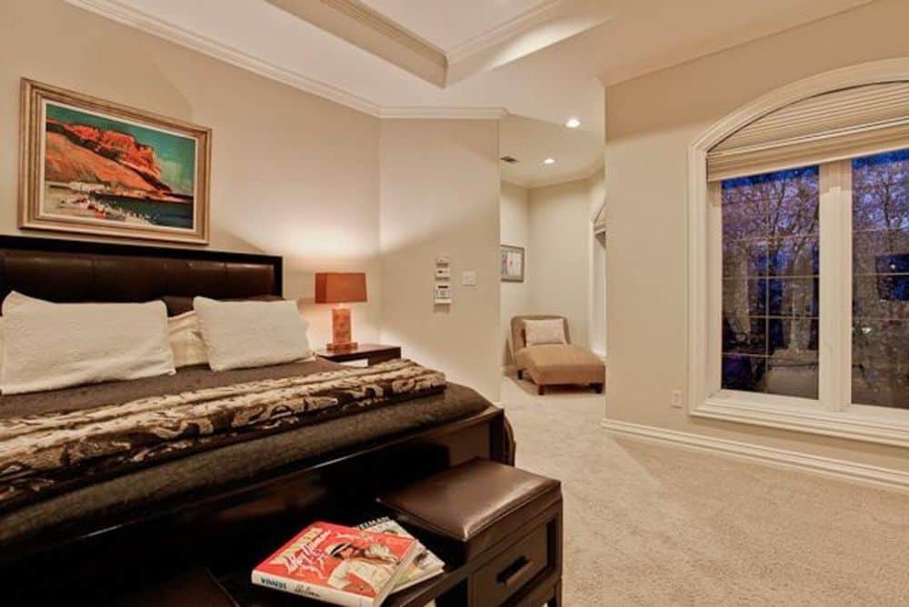 主卧室有一个托盘天花板,现任区域和一个舒适的木制床辅以存储的长椅上。