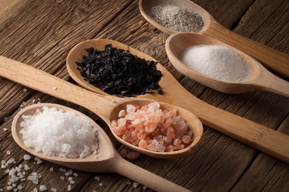 仔细观察各种类型的盐放在木勺上。