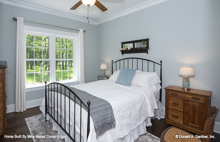 这间卧室有一张金属床、木制床头柜和一扇白色框窗，可以让自然光照进来。