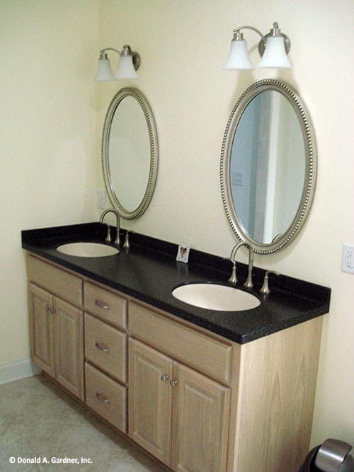 这间浴室设有一个双洗手池梳妆台，上面有圆形镜子和玻璃烛台。