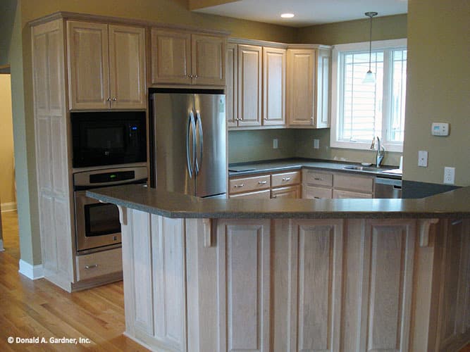厨房提供轻木橱柜，不锈钢电器，和一个弯曲的半岛。