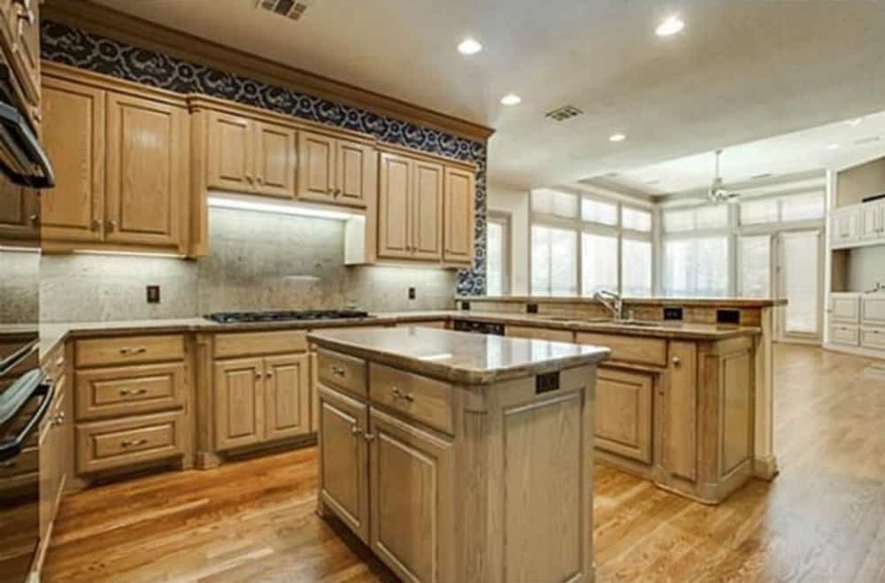 厨房配有花岗岩台面，木制橱柜，硬木地板上方有配套的岛台。