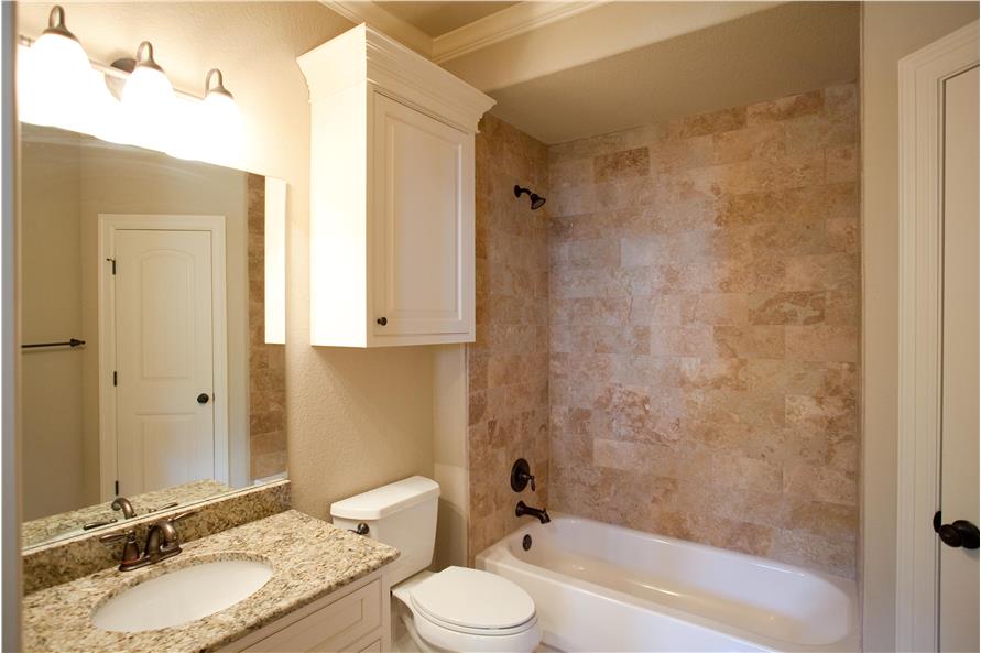 这间浴室配备了一个洗手台、一个浴缸和淋浴组合，以及一个顶部有白色顶置柜的马桶。