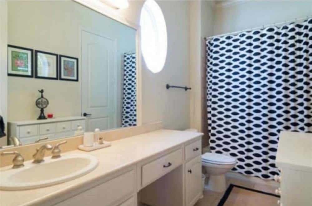浴室有一个洗手台，一个马桶，一个淋浴区隐藏在有图案的窗帘后面。