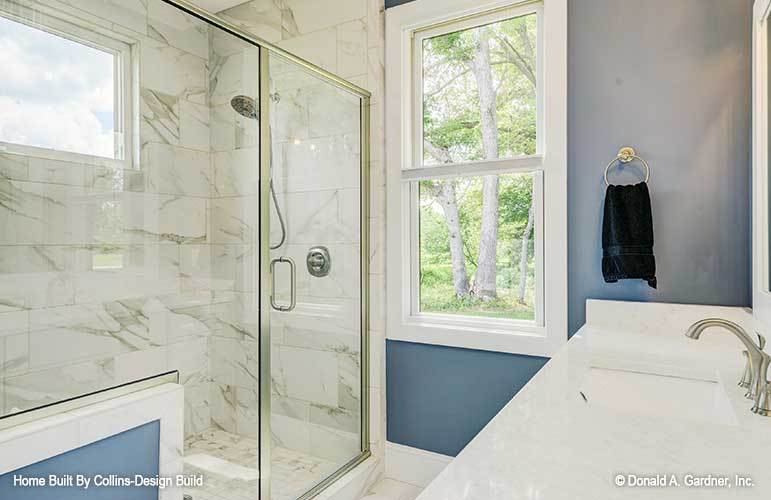 主浴室有一个大理石梳妆台，一个步入式淋浴间，和一个白色框窗，可以让自然光进入。