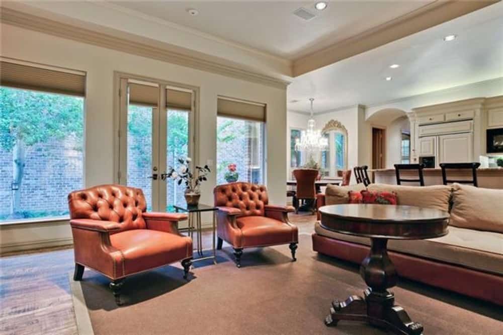 家庭娱乐室，有真皮沙发，簇绒扶手椅和一张圆桌，上面有镶边地毯。