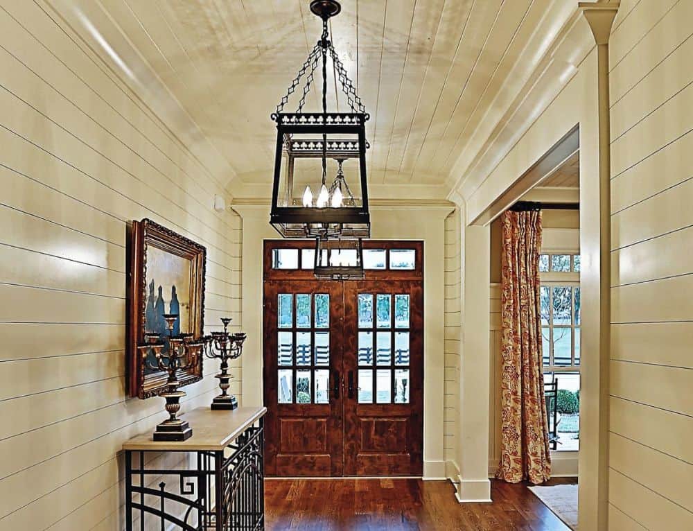 门厅有法式正门，一个锻铁吊坠，和一个木制的顶部控制台桌子装饰着一幅画框。