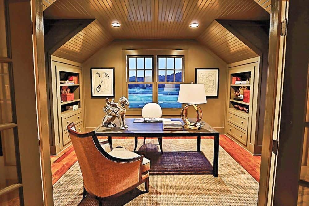 书房里有灰褐色的内置家具，一张大木桌，和一个覆盖着木板的拱形天花板。