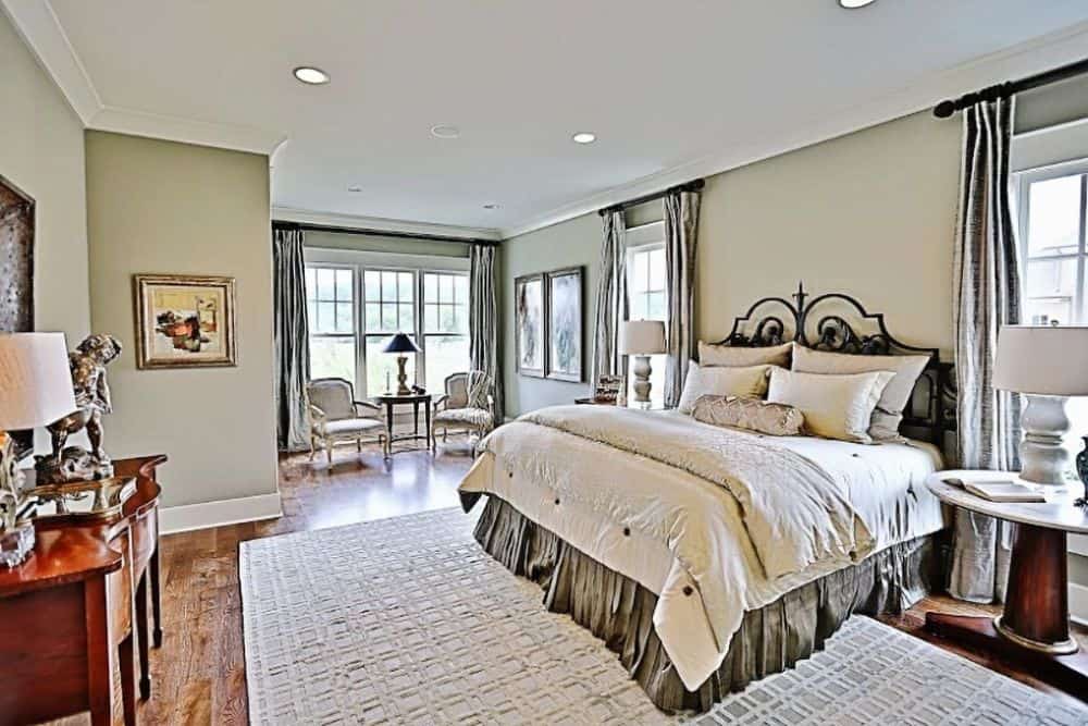 主卧室有圆形靠背椅子和一张带裙边的床，上面有图案的区域地毯。