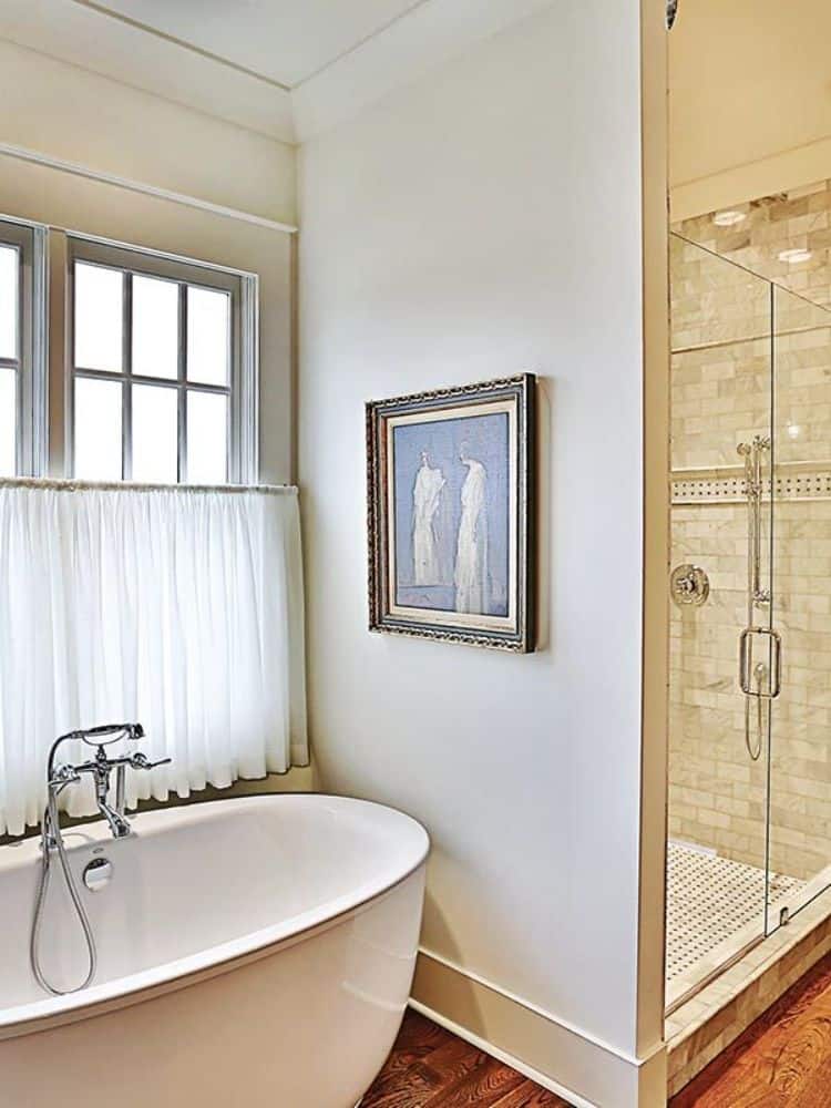 主浴室包括一间步入式淋浴间和一个独立的浴缸，浴缸位于白色框窗下。