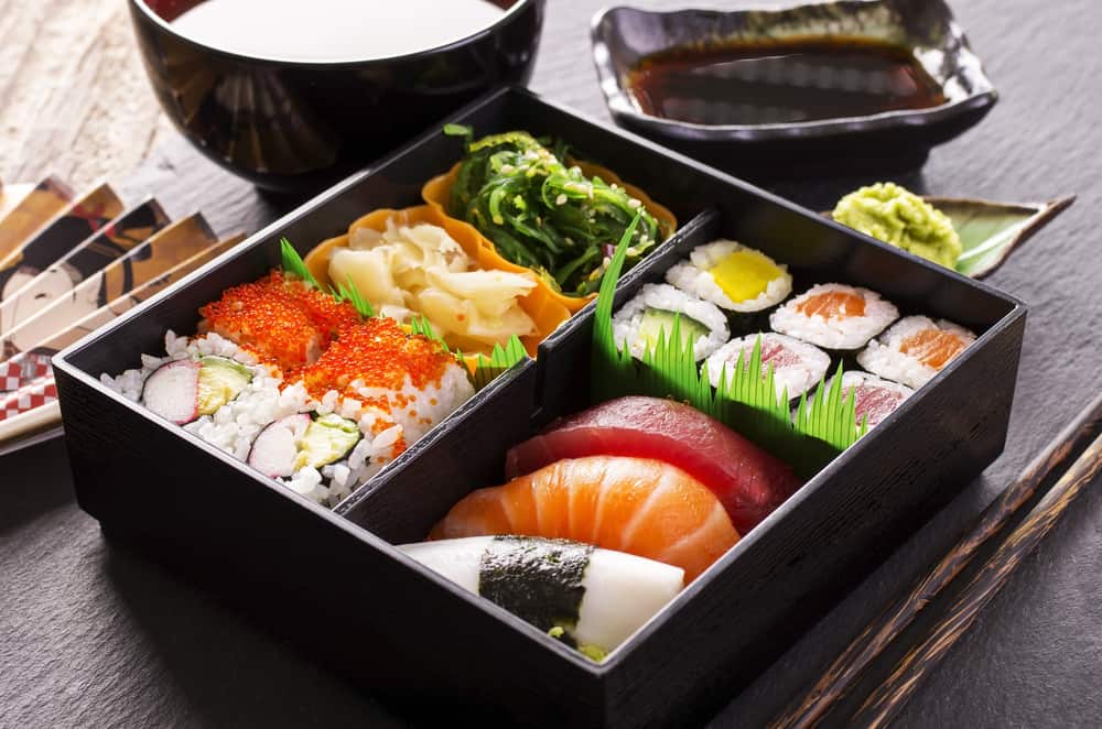 近距离观察一个便当盒，里面有各种寿司和鱼味和味增汤。