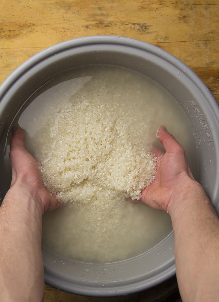 一位厨师正在用传统的清洗方法清洗锅中的米饭。