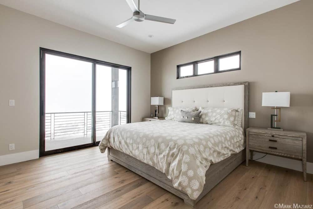 主卧室里有一张舒适的木床，配套的床头柜，还有通往阳台的滑动玻璃门。