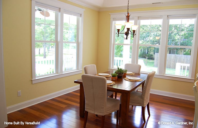 正式的餐厅，有一张木制餐桌，米色软垫椅子，以及可以引入自然光的大窗户。