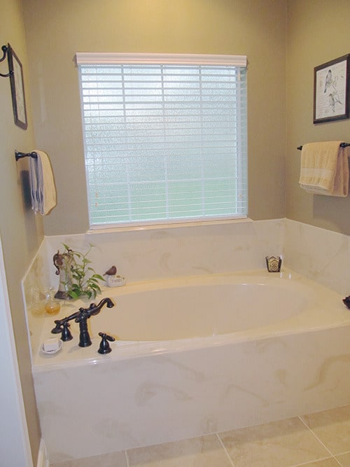 dropin浴缸铁艺设备和大理石环绕瓷砖延长石膏墙壁。