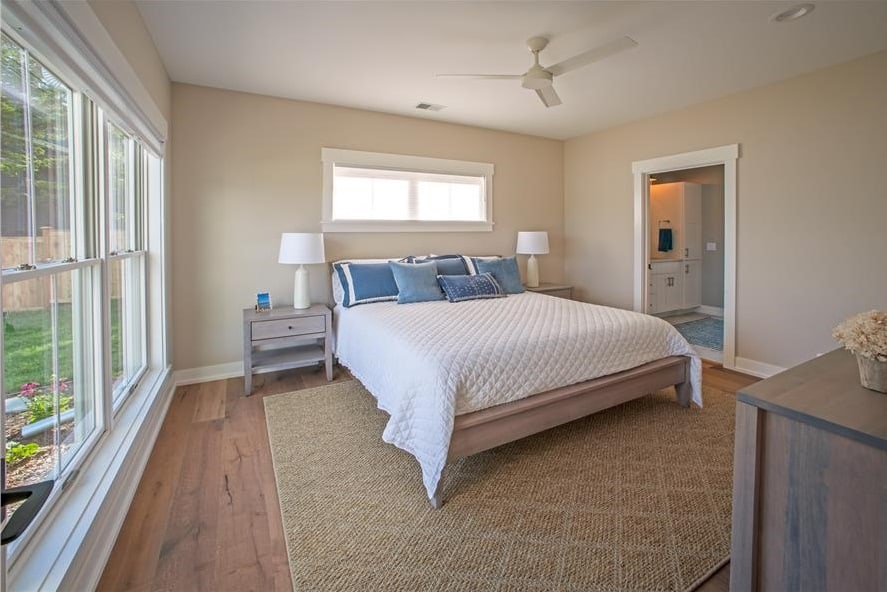 主卧室里有木制家具、一间私人浴室和硬木地板，上面铺着有图案的区域地毯。