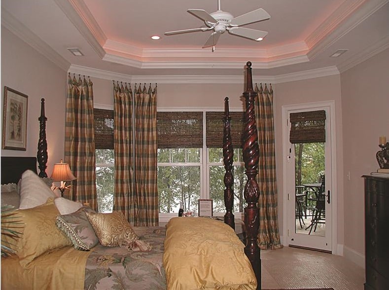 主卧室有一个优雅的托盘天花板，四柱床，和一个飘窗装饰着格子窗帘。