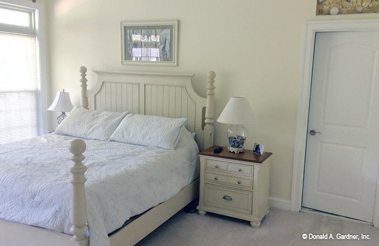 主卧室有一张舒适的白色床和配套的床头柜。