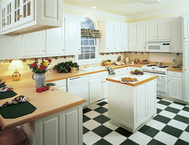 厨房里有白色橱柜，一面拱形镜子，中间有一个小岛台，上面铺着方格地板。