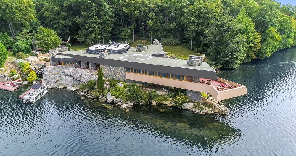 这是房子的鸟瞰图，展示了独特的设计，混凝土结构和水面上的阳台。图片来自Toptenrealestatedeals.com。